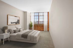 Enfield apartment for rent - A large carpeted bedroom with exposed brick and large windows with natural light
