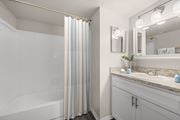 Indialantic apartment for rent - A bathroom with a white tub, sink, and striped shower curtain.