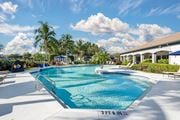 Fort Myers apartment for rent - A large outdoor swimming pool with lounge chairs and an adjacent clubhouse overlooking a body of water