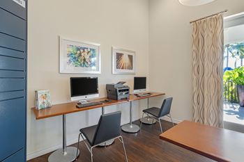 A room with a desk, chairs, and two framed pictures on the wall.