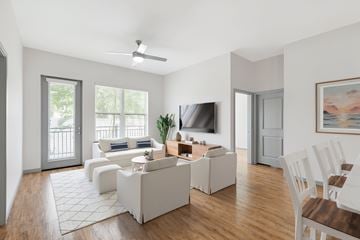 Sarasota apartment for rent - A living room with a white couch, a television, and a painting on the wall.