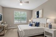 Alpharetta apartment for rent - A bedroom with a large bed, a ceiling fan, and a window with blinds.