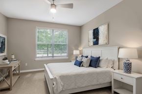 Alpharetta apartment for rent - A bedroom with a large bed, a ceiling fan, and a window with blinds.