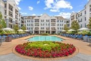 Alpharetta apartment for rent - A large pool surrounded by a flower bed in front of apartment buildings.