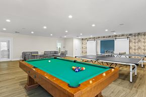 Quincy apartment for rent - A pool table with a green cloth and a white cue ball is in the center of the room.
