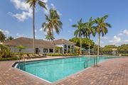 Boynton Beach apartment for rent - A swimming pool surrounded by palm trees and a house.