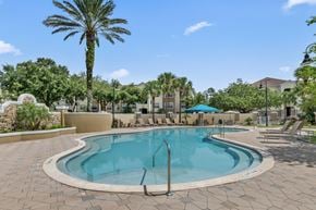 Orange City apartment for rent - A large outdoor swimming pool surrounded by palm trees and lounge chairs.