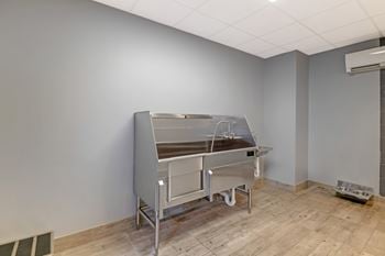 A large, empty room with a stainless steel table in the corner.