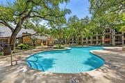 Austin apartment for rent - A swimming pool surrounded by trees and buildings.