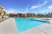 Tucson apartment for rent - A large swimming pool with a diving board and a building in the background.