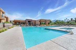 Tucson apartment for rent - A large swimming pool with a diving board and a building in the background.