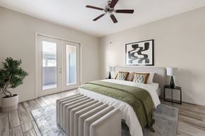 Tucson apartment for rent - A bedroom with a bed, pillows, a ceiling fan, and a plant.