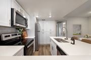 Tucson apartment for rent - A modern kitchen with white cabinets and a black stove top.