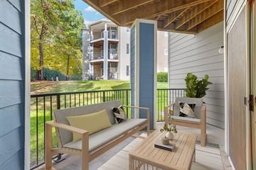 Charlotte apartment for rent - A balcony with a couch, chair, and table with a plant on it.