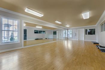 A spacious room with wooden floors and large windows.