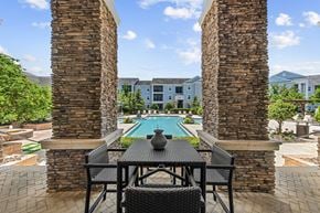 Land O Lakes apartment for rent - A table with chairs is in the foreground of a pool area.