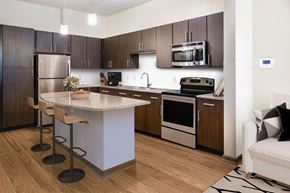 Orlando apartment for rent - a kitchen with dark wood cabinets and a white island with a granite countertop at The Rialto, Orlando, FL, 32819