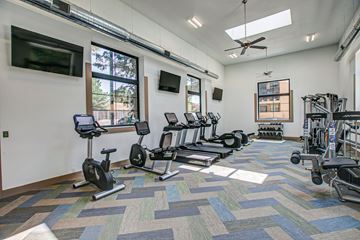 Santa Fe apartment for rent - A spacious gym with a variety of exercise equipment and a television mounted on the wall.