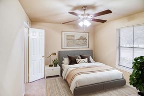 Austin apartment for rent - a bedroom with a large bed and a ceiling fan at Village Oaks Apartments, Texas, 78759
