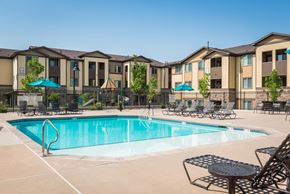 Colorado Springs apartment for rent - our apartments have a swimming pool with chairs and umbrellas at Estate at Woodmen Ridge, Colorado Springs, CO 80923