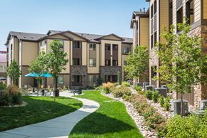 Colorado Springs apartment for rent - a sidewalk leading to an apartment building with lush green grass and trees at Estate at Woodmen Ridge, Colorado Springs, CO 80923
