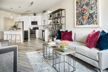 Charlotte apartment for rent - A modern living room with a grey couch and a large abstract painting on the wall.