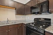 Colorado Springs apartment for rent - A black microwave is mounted above a black stove in a kitchen.