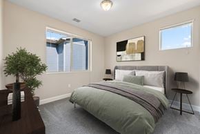 Colorado Springs apartment for rent - A bedroom with a bed, nightstand, and a plant.