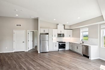 A kitchen with white appliances and wooden floors.