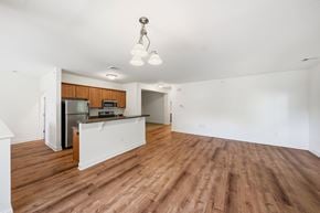 Albany apartment for rent - A room with wooden floors and a kitchen area with a refrigerator, microwave, and oven.