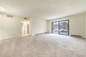 Queensbury apartment for rent - a spacious living room with a large window and carpeted flooring