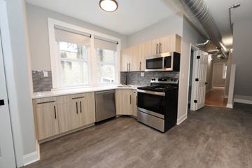 Philadelphia apartment for rent - a kitchen with white cabinets and a stove and a window