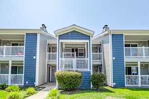 Greenville apartment for rent - A blue and white building with a red car parked in front.