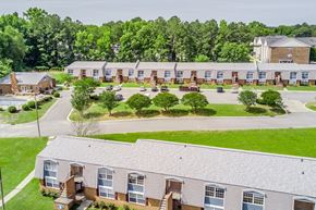 Greenville apartment for rent - A large building complex with a parking lot in front.