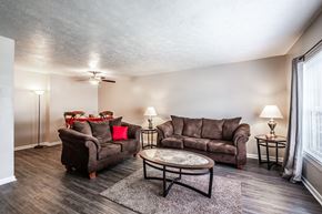 Greenville apartment for rent - A living room with a brown couch, a coffee table, and a lamp.