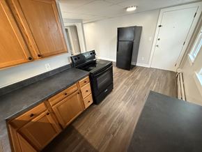 Concord apartment for rent - A kitchen with wooden cabinets and black appliances.