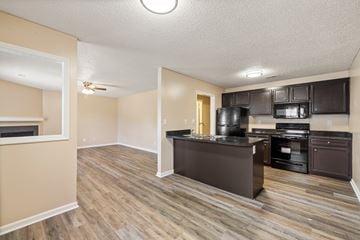 Greenville apartment for rent - A kitchen with dark wood cabinets and a black countertop.