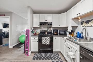 Concord apartment for rent - A kitchen with white cabinets and a black and white rug on the floor.