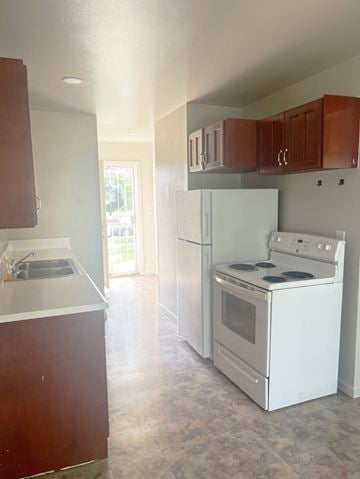 Inkster apartment for rent - an empty kitchen with white appliances and wooden cabinets