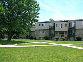 Clinton Twp apartment for rent - an exterior view of an apartment building with grass and trees