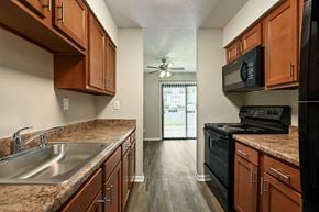 Topeka apartment for rent - A kitchen with wooden cabinets and a black stove top oven.