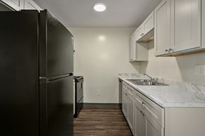 Topeka apartment for rent - A kitchen with a black refrigerator and white cabinets.