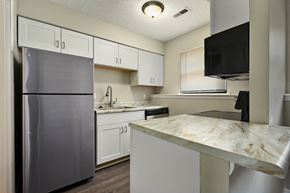 Lawrence apartment for rent - a kitchen with white cabinets and stainless steel appliances and a marble counter top