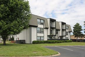 Topeka apartment for rent - Apartment building with a black fence and green trees in front.