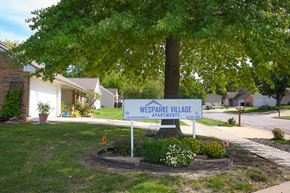Topeka apartment for rent - A sign for Wesparke Village Apartments stands in a landscaped area.