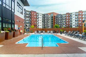 Winnipeg apartment for rent - A large swimming pool surrounded by lounge chairs in front of apartment buildings.