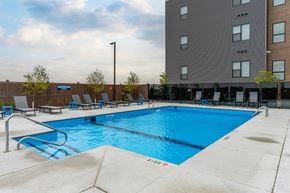 Winnipeg apartment for rent - A large blue swimming pool in front of a tall building.