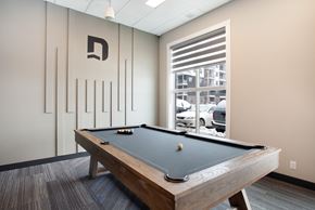 Calgary apartment for rent - A pool table in a room with a window showing a parking lot outside.