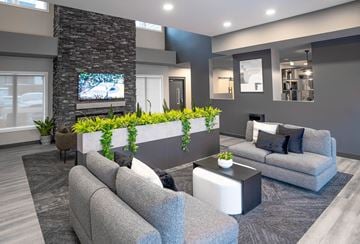 Calgary townhouse for rent - A modern living room with grey couches and a stone pillar.