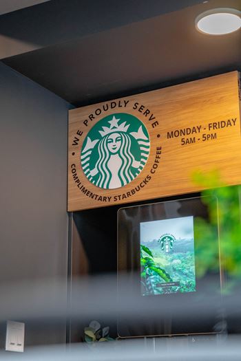 A starbucks sign is hanging on the wall.